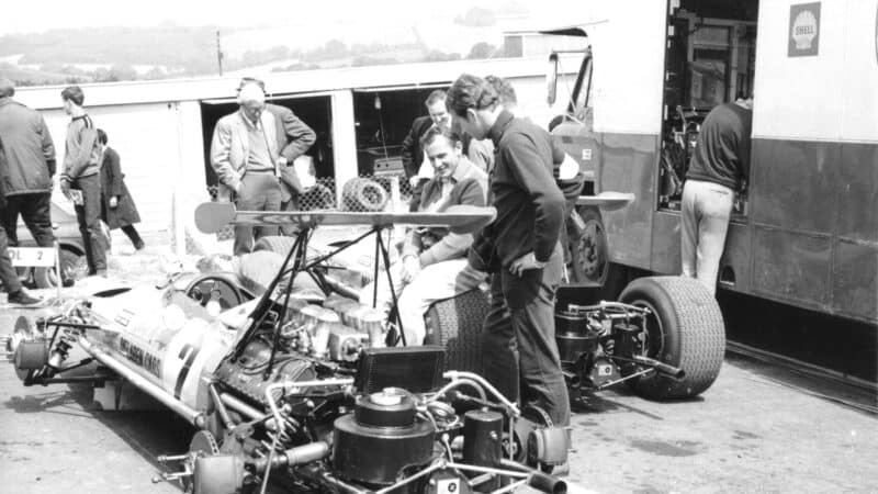 Bruce McLaren, sitting on rear tyre